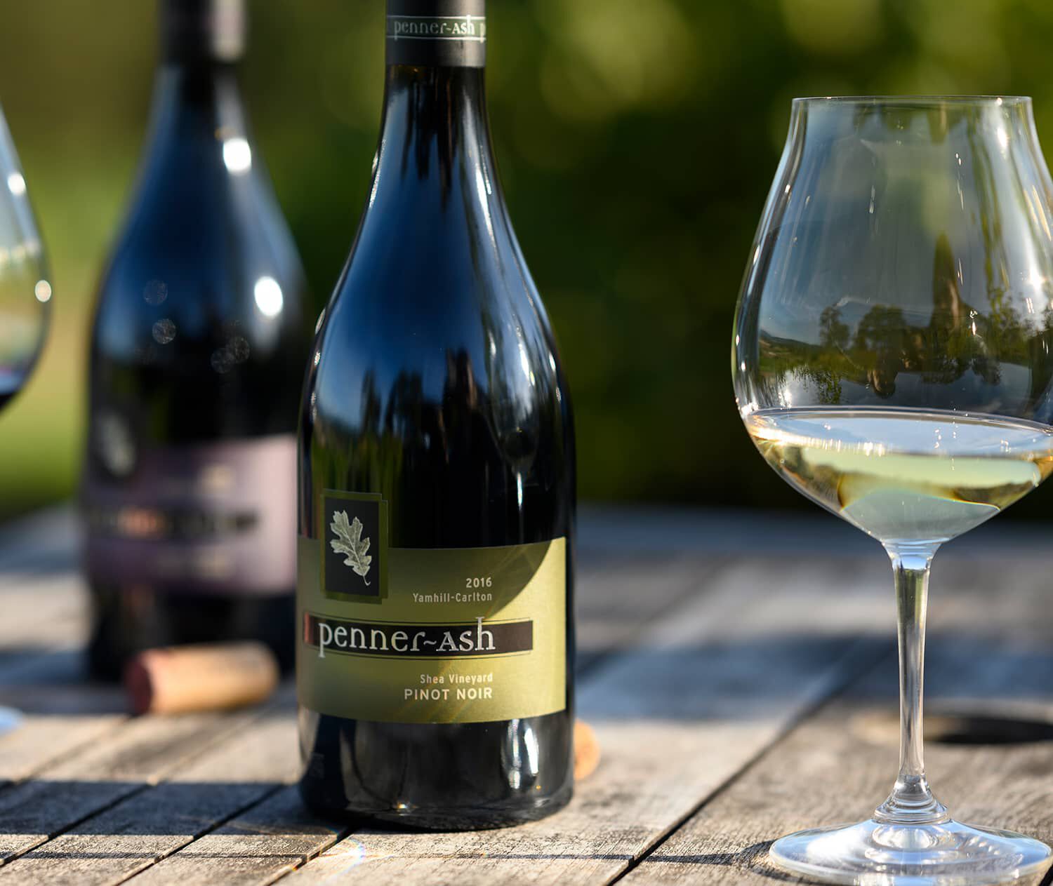 A close up of a bottle of Penner-Ash wine and a glass of white wine.