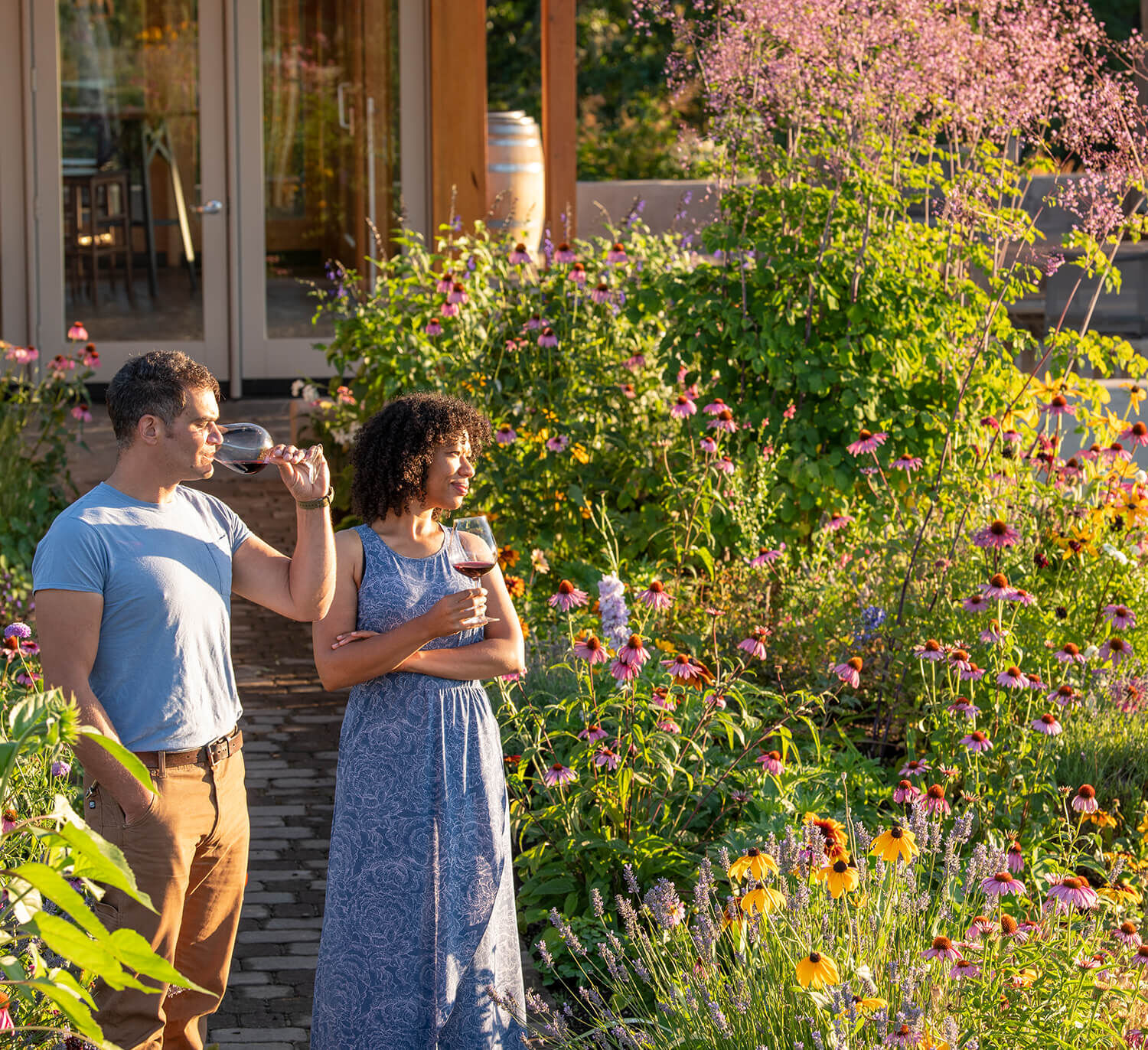 A couple drinking a glass of Penner-ash wine in the Penner-Ash Estate Garden.