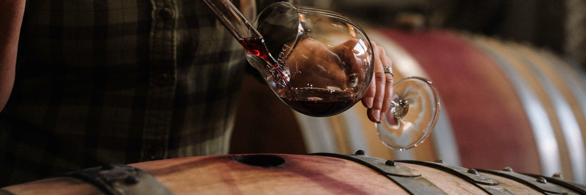 A person taking white out of a wine barrel.