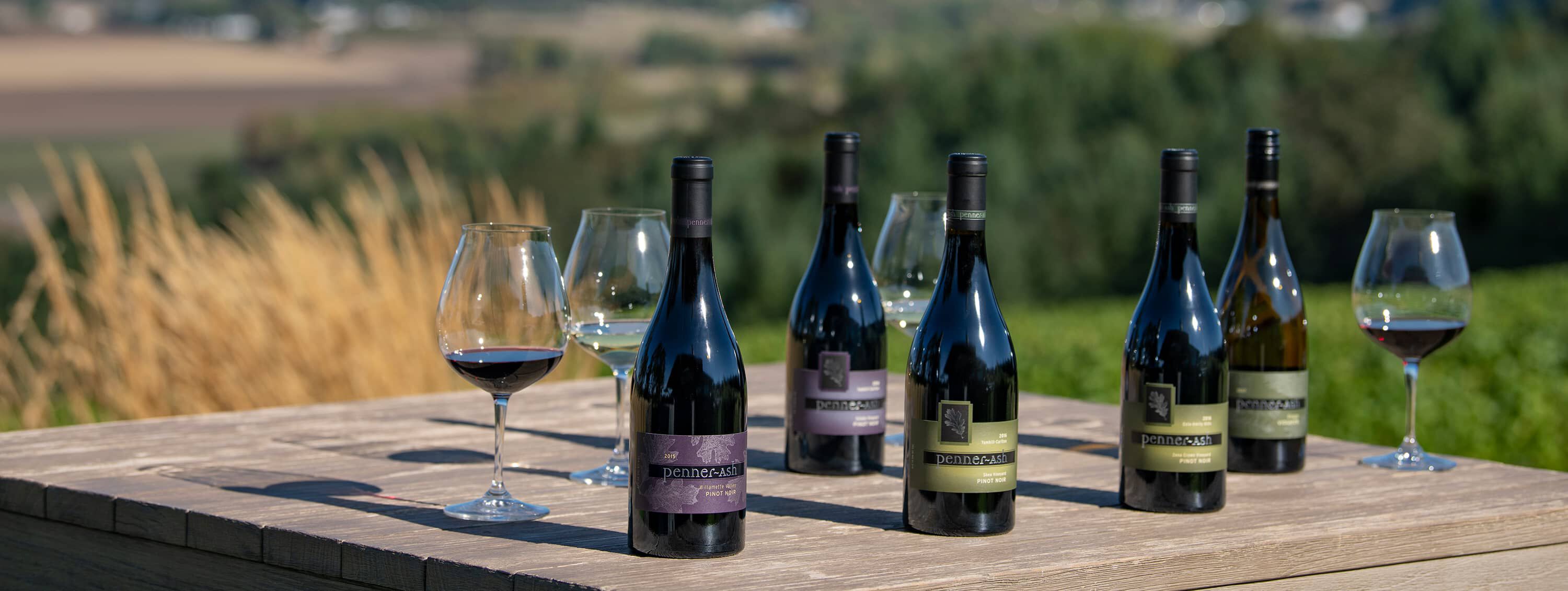 A table outside with bottles of Penner-Ash wine standing on it.